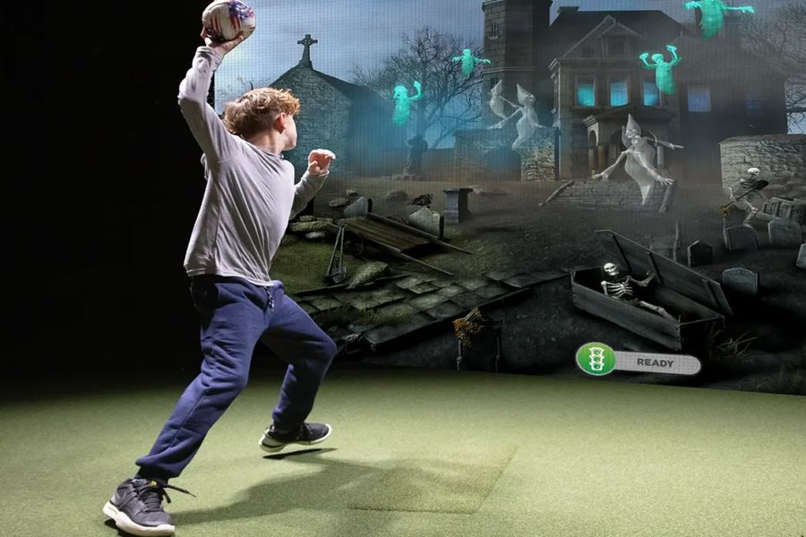 Young player throwing a football at a simulator screen during a Multi-Sport game